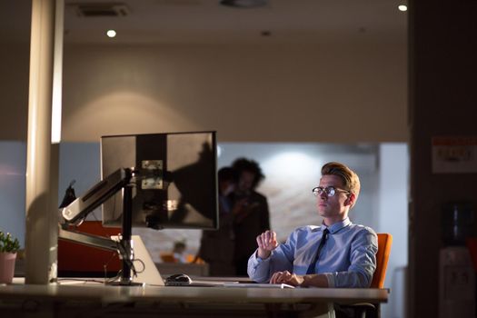 Young man working on computer at night in dark office. The designer works in the later time.