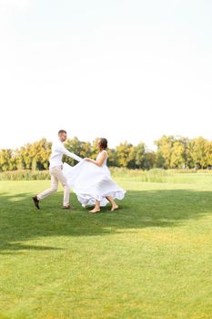 Groom and bride dancing on grass. Concept of wedding photo session on open air and nature.