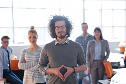 Portrait of smiling young casuall businessman with colleagues in background at the office