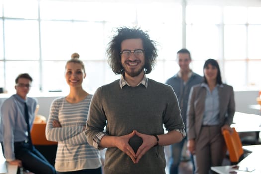 Portrait of smiling young casuall businessman with colleagues in background at the office