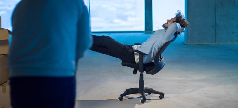 young businessman on construction site taking a break while checking documents and business workflow with cardboard boxes around him in new startup office