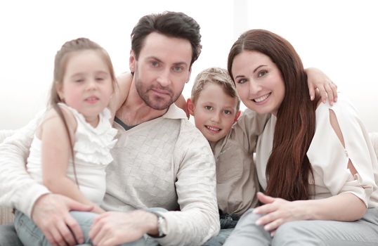 parents hug their children sitting on the couch.the concept of family
