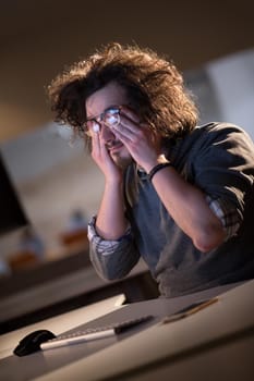 A time for relax. Young tired casual businessman relaxing at the desk in his night office