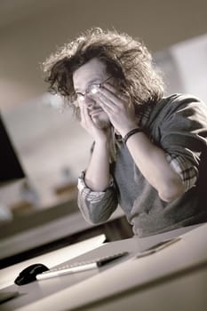 A time for relax. Young tired casual businessman relaxing at the desk in his night office