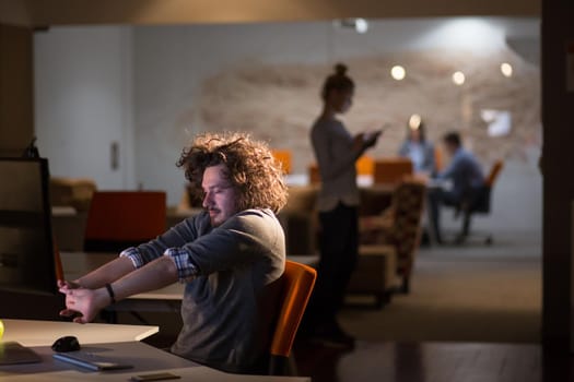 A time for relax. Young tired casual businessman relaxing at the desk in his night office