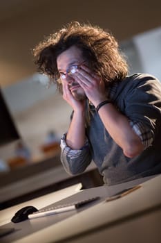 A time for relax. Young tired casual businessman relaxing at the desk in his night office