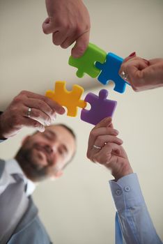 business people group assembling jigsaw puzzle and represent team support and help concept, top view perspective at modern bright office interior