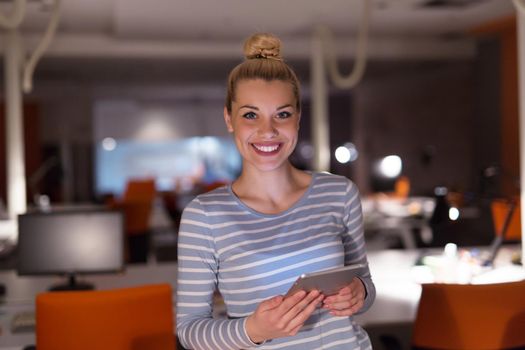 young female entrepreneur working on digital tablet in night office