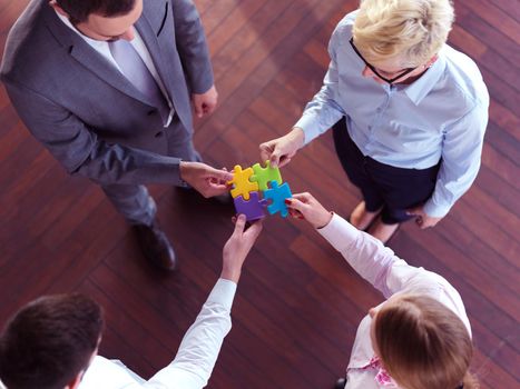 business people group assembling jigsaw puzzle and represent team support and help concept, top view at modern office interior