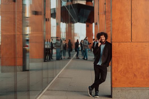 Happy student with afro haircut walking on campus while wearing his manbag and his headphones.