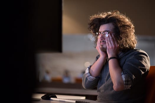 A time for relax. Young tired casual businessman relaxing at the desk in his night office