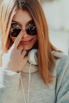 a woman in sunglasses enjoys a walk in the city while listening to music on her headphones