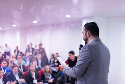 rear view of young successful businessman at business conference room with public giving presentations. Audience at the conference hall. Entrepreneurship club