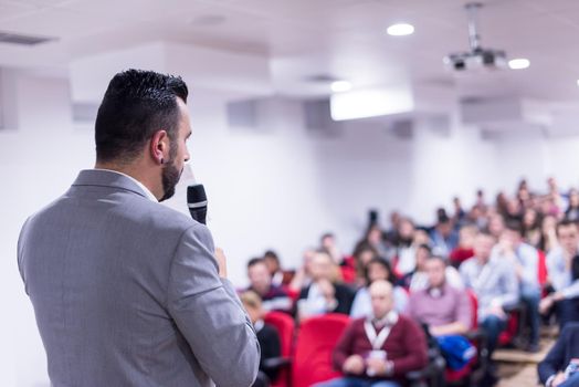 rear view of young successful businessman at business conference room with public giving presentations. Audience at the conference hall. Entrepreneurship club