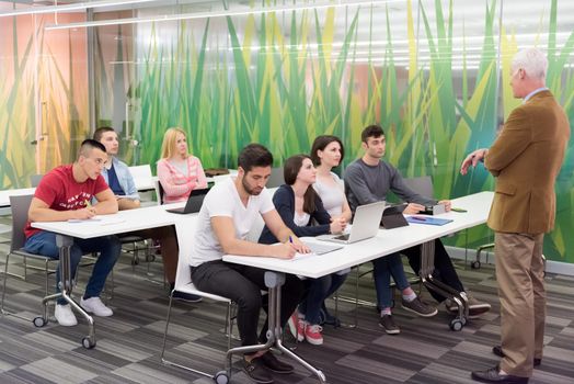 group of students study with professor in modern school classroom