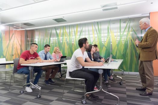 group of students study with professor in modern school classroom