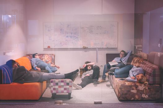 group of young casual software developer sleeping on  sofa during a work break in creative startup office