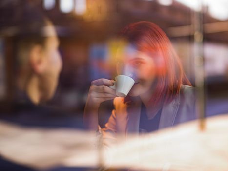 Two women are in the cafeteria drinking coffee and talking. Business meeting