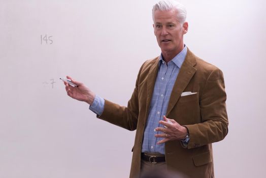 portrait of confident teacher solving problems on whiteboard in classroom