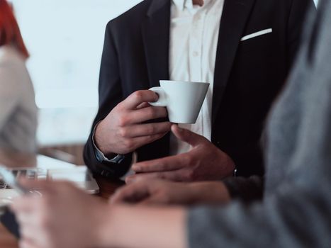 macro photo of a businessman in a suit holding a cup of coffee