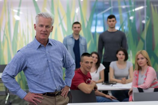 portrait of confident teacher,  students group in background