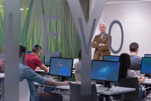 handsome mature teacher and students in computer lab classroom