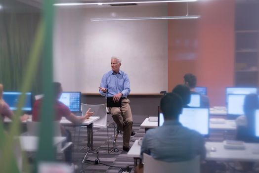 handsome mature teacher and students in computer lab classroom