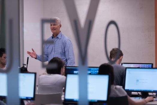 handsome mature teacher and students in computer lab classroom