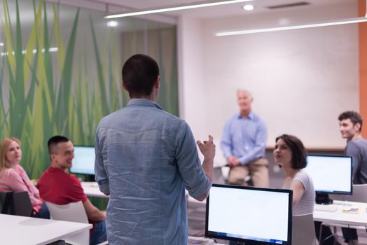 student answering a question in classroom, mature teacher and students in computer lab classroom