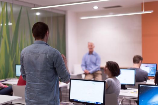 student answering a question in classroom, mature teacher and students in computer lab classroom