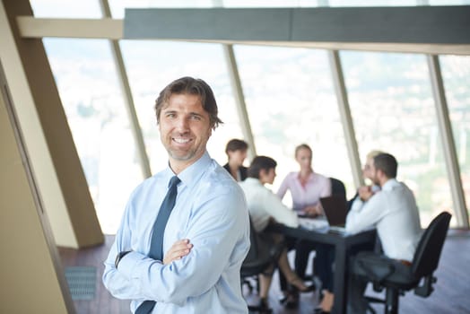 handosme business manportrait  at modern bright office indoors with his team in group working together in background