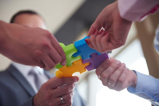 business people group assembling jigsaw puzzle and represent team support and help concept, top view perspective at modern bright office interior