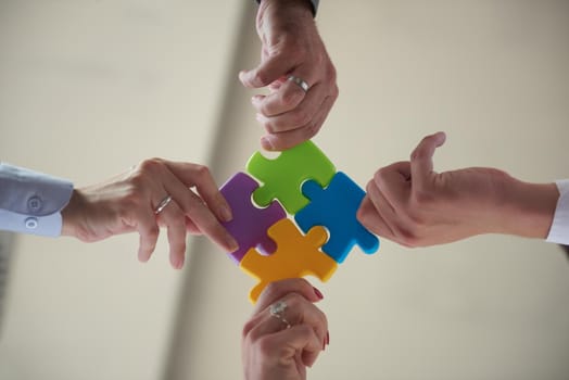 business people group assembling jigsaw puzzle and represent team support and help concept, top view perspective at modern bright office interior