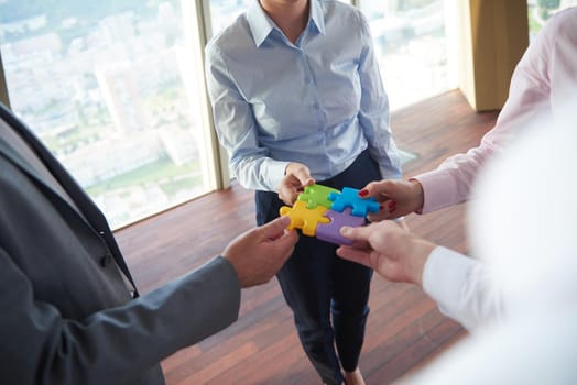 business people group assembling jigsaw puzzle and represent team support and help concept, top view perspective at modern bright office interior