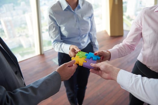 business people group assembling jigsaw puzzle and represent team support and help concept, top view perspective at modern bright office interior