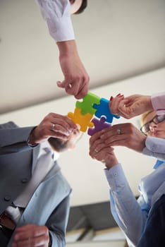 business people group assembling jigsaw puzzle and represent team support and help concept, top view perspective at modern bright office interior