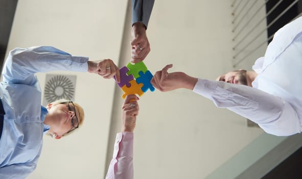 business people group assembling jigsaw puzzle and represent team support and help concept, top view perspective at modern bright office interior