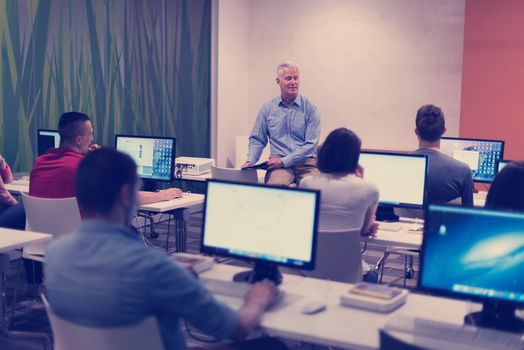 handsome mature teacher and students in computer lab classroom