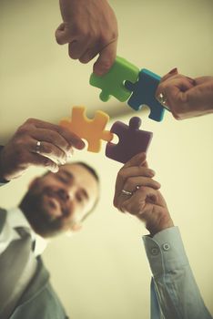 business people group assembling jigsaw puzzle and represent team support and help concept, top view perspective at modern bright office interior