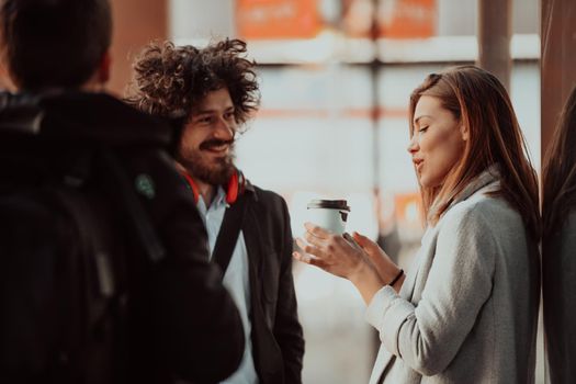 two young people are drinking coffee and taking a break from work in front of the company where they work