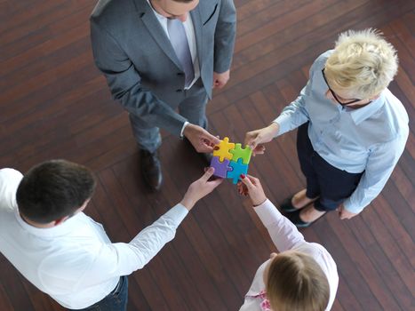 business people group assembling jigsaw puzzle and represent team support and help concept, top view at modern office interior