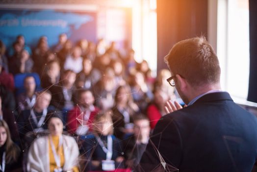 rear view of young successful businessman at business conference room with public giving presentations. Audience at the conference hall. Entrepreneurship club