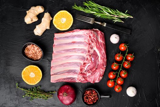 Raw meat rib rack set, on black dark stone table background, top view flat lay
