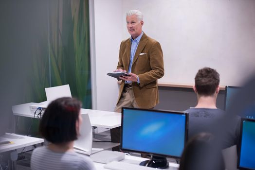 handsome mature teacher and students in computer lab classroom