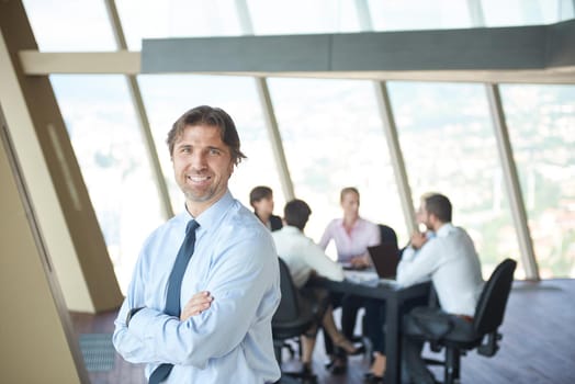 handosme business manportrait  at modern bright office indoors with his team in group working together in background