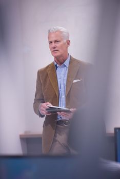 handsome mature teacher and students in computer lab classroom