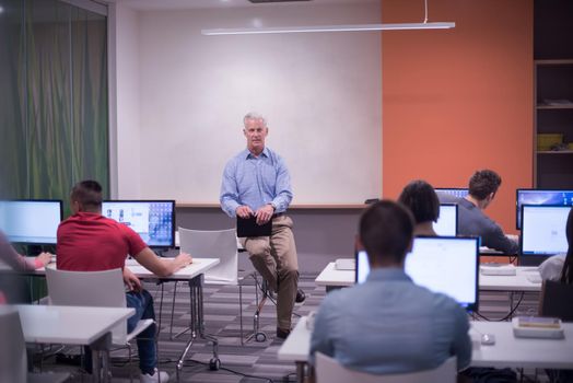 handsome mature teacher and students in computer lab classroom