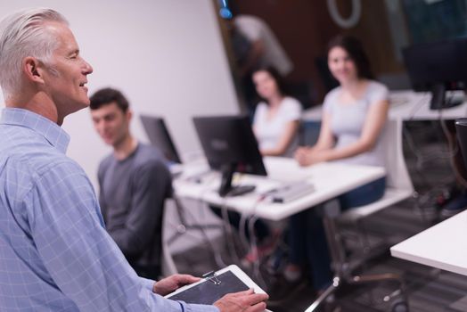 handsome mature teacher and students in computer lab classroom