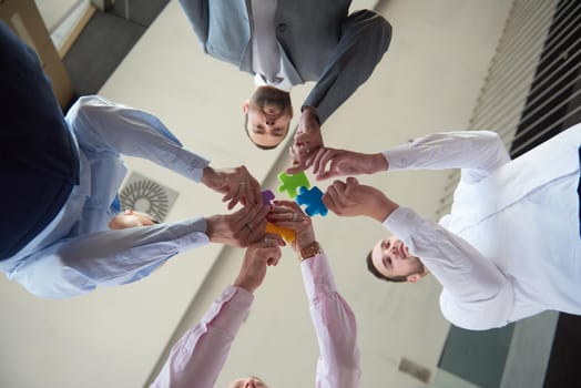 business people group assembling jigsaw puzzle and represent team support and help concept, top view perspective at modern bright office interior