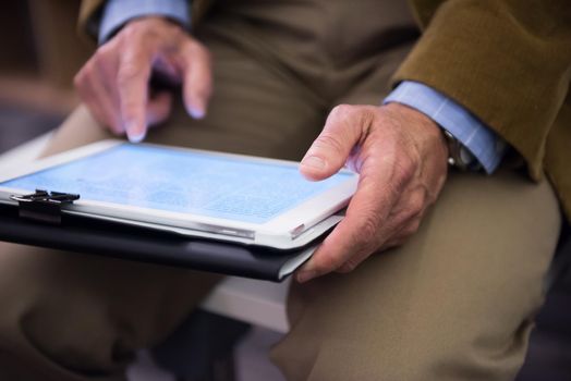 Closeup of mature hands holding tablet. Teacher with students in classroom